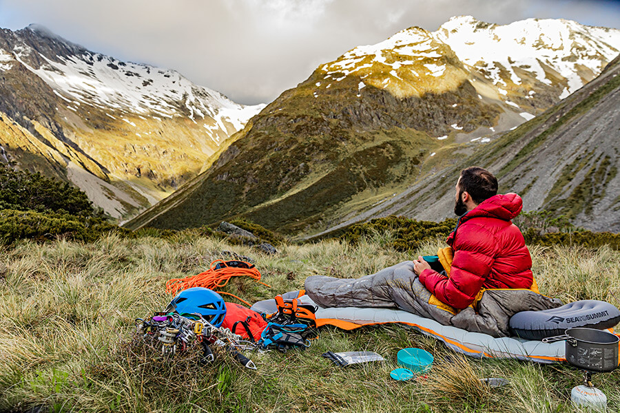 Kletterer in den Bergen im Schlafsack von Ausrüstung umgeben