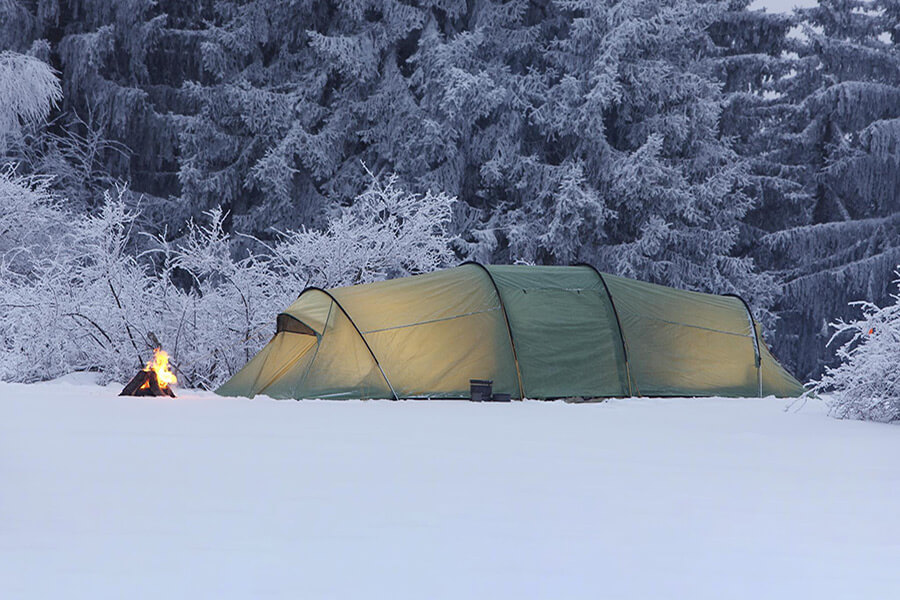 Familienzelt in Winterlandschaft mit Lagerfeuer