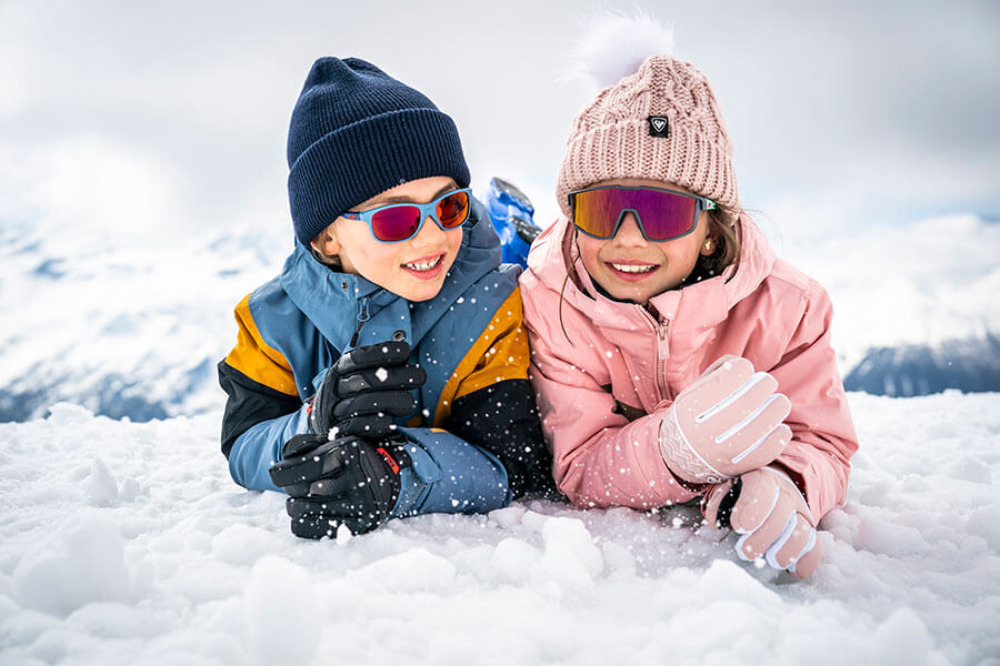 zwei Kinder mit Sonnenbrillen im Schnee