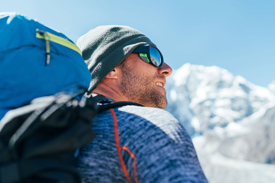Wanderer mit Sonnenbrille blickt auf schneebedeckte Berge