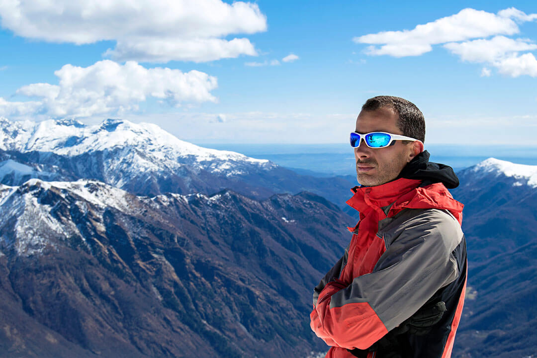 Mann mit ernstem Blick und Sonnenbrille in einer schönen Berglandschaft