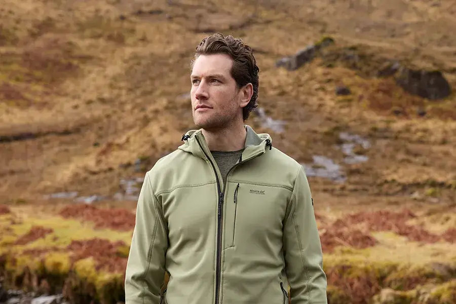 Mann mit Softshelljacke an Bachlauf